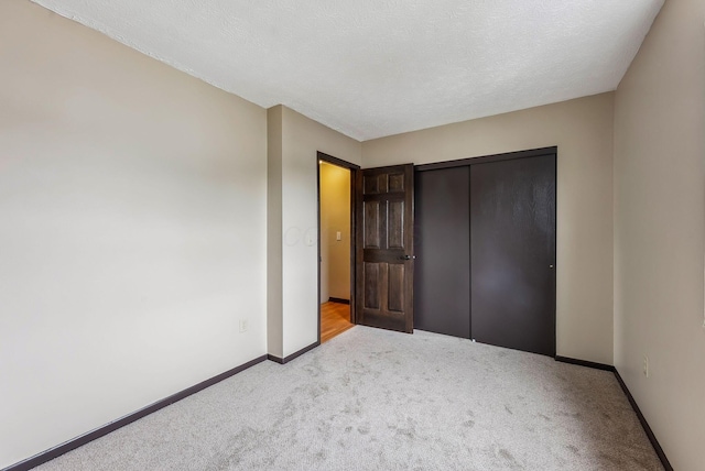 unfurnished bedroom with light colored carpet, baseboards, and a closet