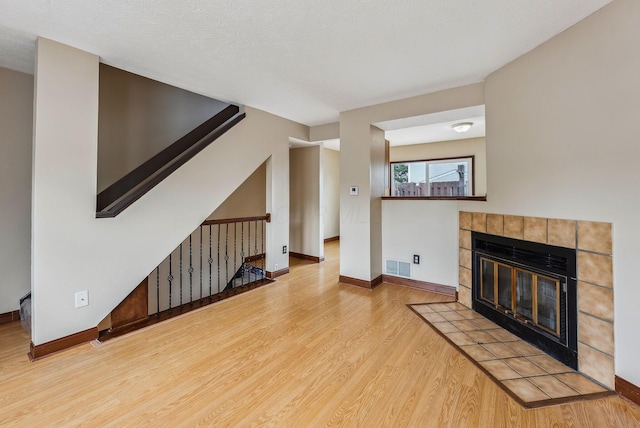 unfurnished living room with wood finished floors, baseboards, and a fireplace