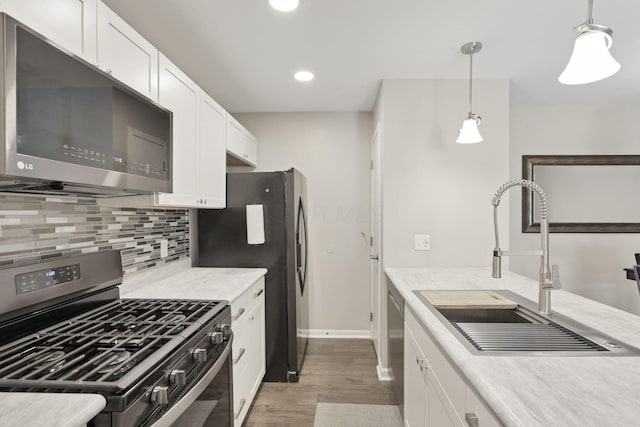 4712 Shalers Dr Unit 54A, Columbus, OH 43228 - kitchen with appliances with stainless steel finishes, a sink, wood finished floors, tasteful backsplash, and white cabinetry