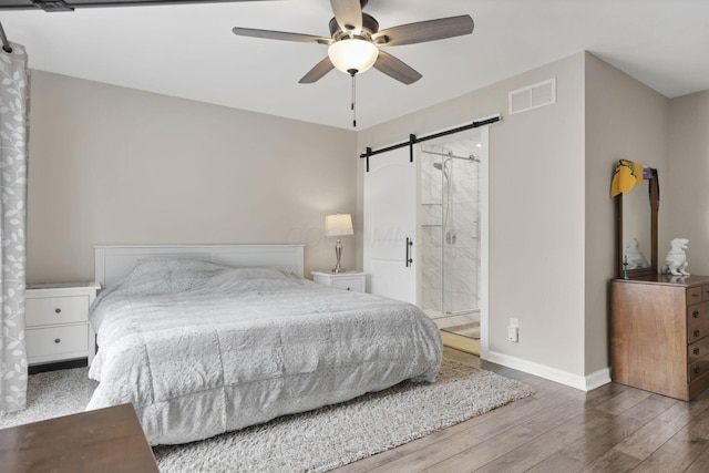 4712 Shalers Dr Unit 54A, Columbus, OH 43228 - bedroom with a barn door, wood finished floors, baseboards, ceiling fan, and ensuite bathroom