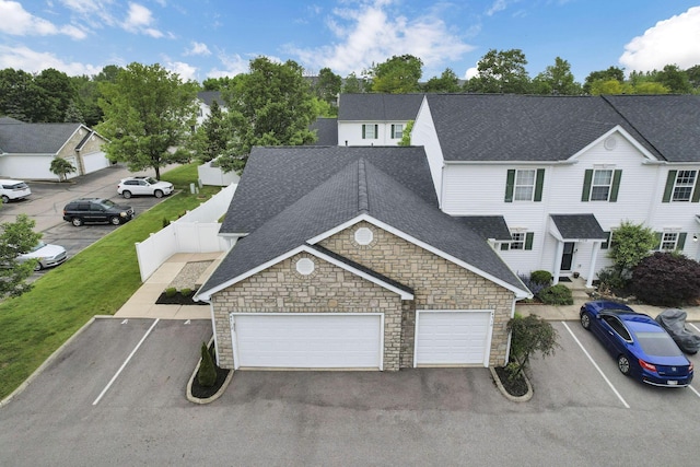 4712 Shalers Dr Unit 54A, Columbus, OH 43228 - view of front of home with a shingled roof, stone siding, fence, an attached garage, and asphalt driveway