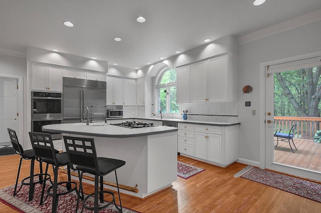8259 Spruce Needle Ct, Columbus, OH 43235 - kitchen with appliances with stainless steel finishes, a kitchen bar, white cabinetry, light wood-type flooring, and ornamental molding