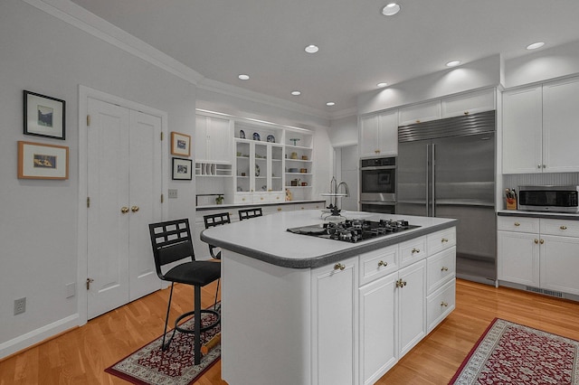 8259 Spruce Needle Ct, Columbus, OH 43235 - kitchen featuring appliances with stainless steel finishes, crown molding, white cabinets, light wood finished floors, and a center island