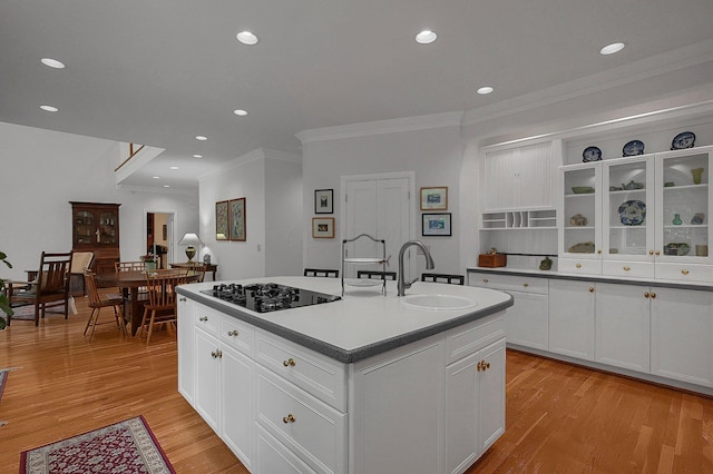 8259 Spruce Needle Ct, Columbus, OH 43235 - kitchen with black cooktop, a sink, ornamental molding, a kitchen island with sink, and light wood-style floors