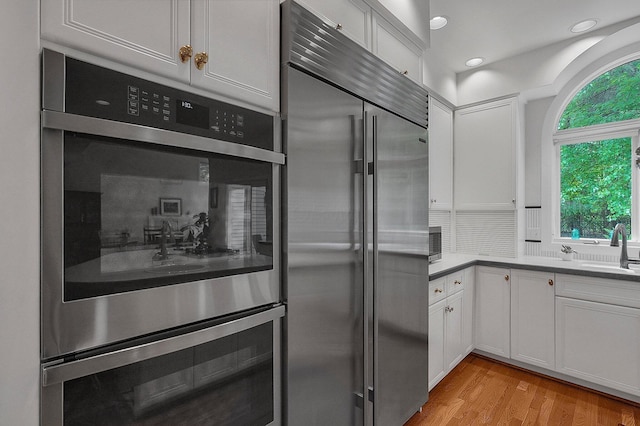 8259 Spruce Needle Ct, Columbus, OH 43235 - kitchen featuring appliances with stainless steel finishes, white cabinetry, light wood-style flooring, recessed lighting, and a sink