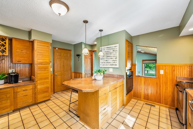 12502 Barbara Dr, Kenton, OH 43326 - kitchen with wainscoting, a peninsula, wooden walls, black oven, and a textured ceiling