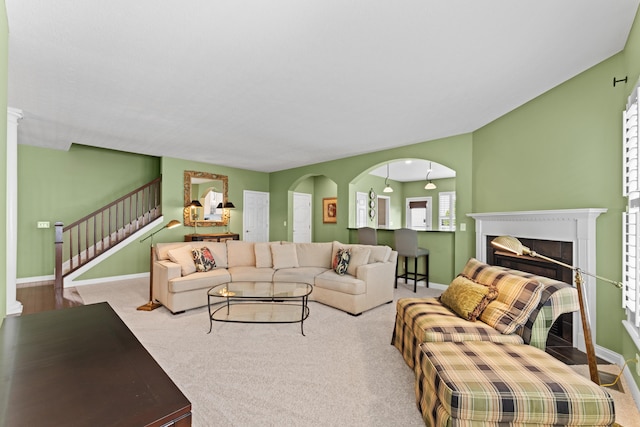 carpeted living area featuring stairs, a fireplace, and baseboards