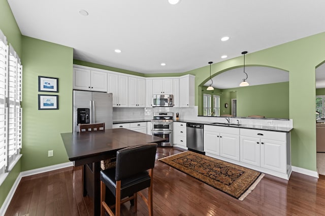kitchen with stainless steel appliances, a sink, baseboards, white cabinetry, and recessed lighting