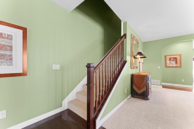 stairs with arched walkways, baseboards, and wood finished floors