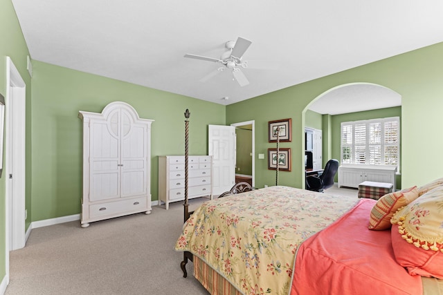 carpeted bedroom featuring arched walkways, baseboards, and a ceiling fan