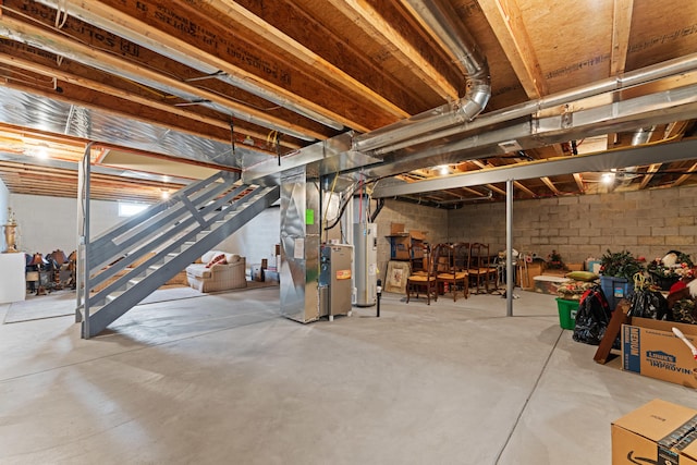 unfinished below grade area featuring heating unit, stairs, electric water heater, and concrete block wall
