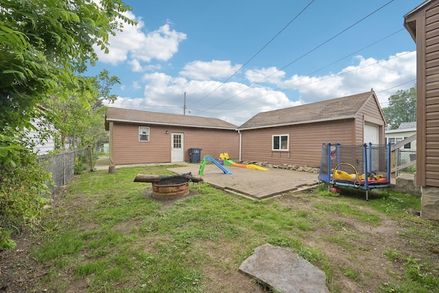 back of property with an outdoor fire pit and a garage