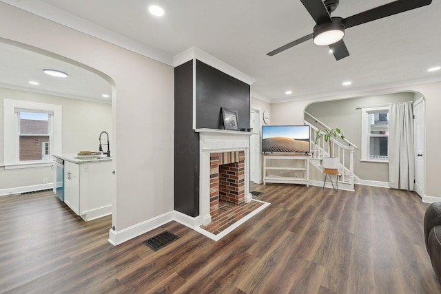 living room with arched walkways, a fireplace, baseboards, ornamental molding, and recessed lighting