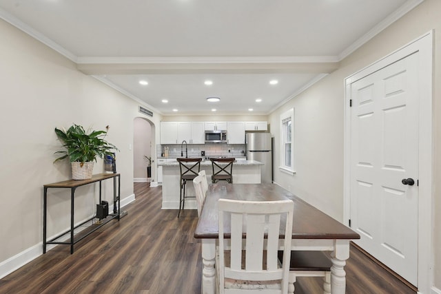 dining space with arched walkways, dark wood-style floors, baseboards, recessed lighting, and crown molding