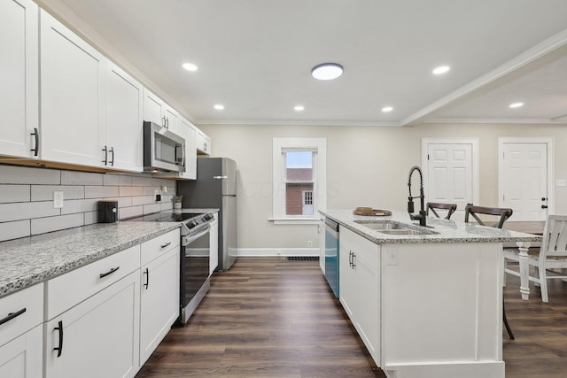 kitchen featuring appliances with stainless steel finishes, a sink, tasteful backsplash, dark wood-style flooring, and ornamental molding