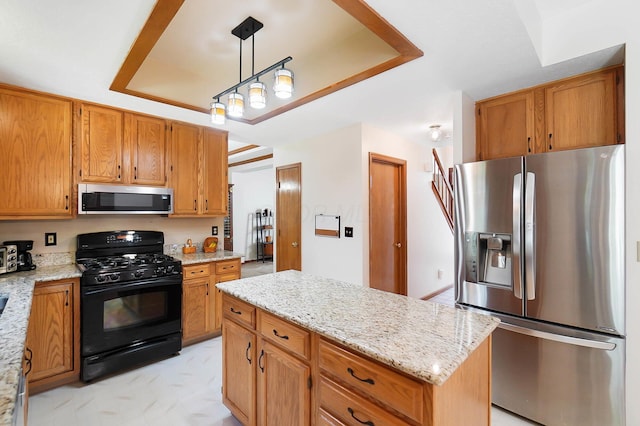 kitchen featuring stainless steel appliances, a tray ceiling, hanging light fixtures, light stone countertops, and brown cabinetry