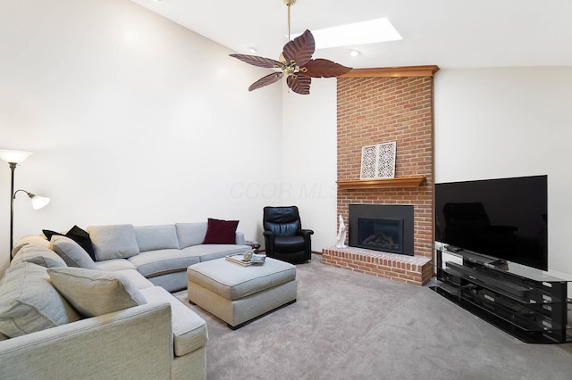 carpeted living area with a ceiling fan, a fireplace, and a skylight