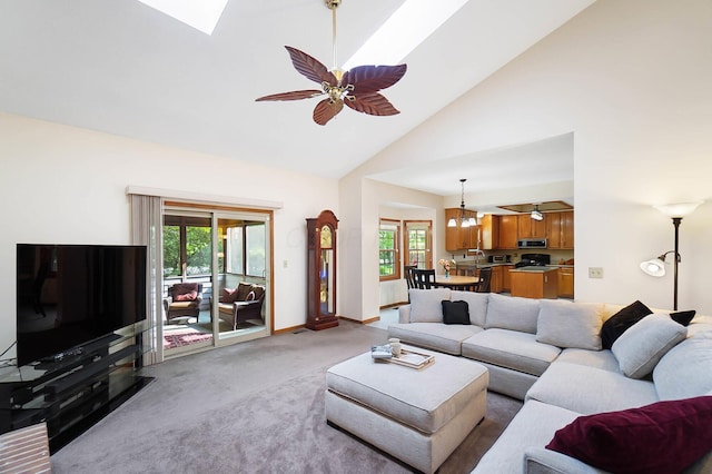 living room with light colored carpet, healthy amount of natural light, a skylight, high vaulted ceiling, and a ceiling fan