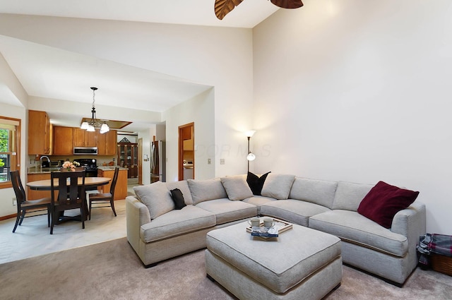 living area featuring light carpet, a chandelier, lofted ceiling, and a ceiling fan