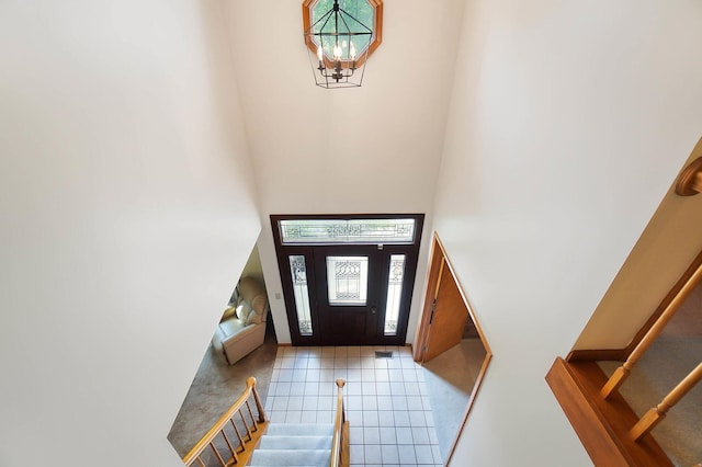 foyer with stairway, a towering ceiling, a chandelier, and tile patterned floors