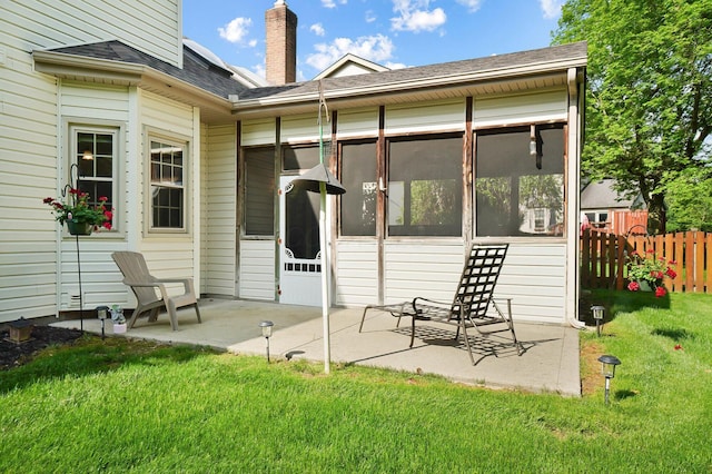 back of property featuring a sunroom, a patio area, a chimney, and a shingled roof