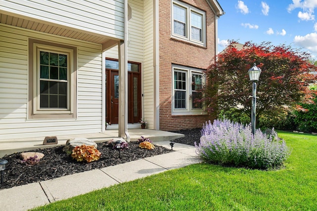 property entrance with brick siding and a lawn