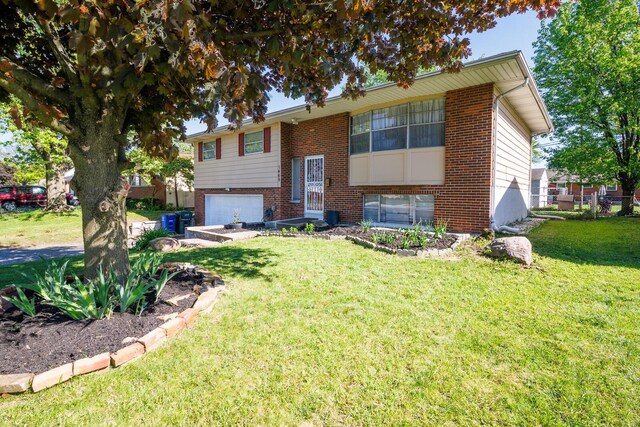 1469 Sandalwood Pl, Columbus, OH 43229 - bi-level home with brick siding, an attached garage, a front yard, and cooling unit