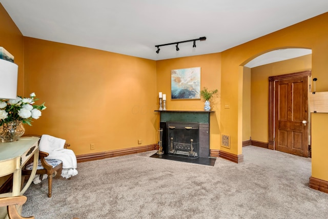 1042 Neil Ave, Columbus, OH 43201 - living room with carpet floors, arched walkways, a fireplace with flush hearth, track lighting, and baseboards