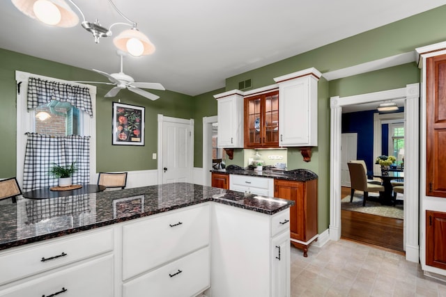 1042 Neil Ave, Columbus, OH 43201 - kitchen featuring a ceiling fan, white cabinetry, dark stone countertops, and glass insert cabinets
