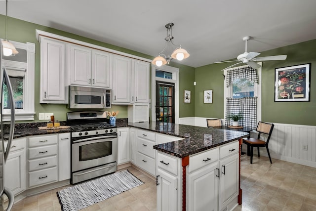 1042 Neil Ave, Columbus, OH 43201 - kitchen featuring stainless steel appliances, a peninsula, ceiling fan, white cabinetry, and hanging light fixtures