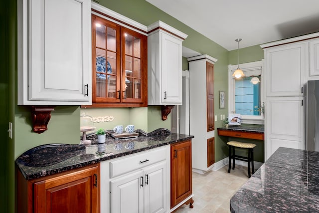 1042 Neil Ave, Columbus, OH 43201 - kitchen with white cabinetry, glass insert cabinets, hanging light fixtures, dark stone countertops, and freestanding refrigerator
