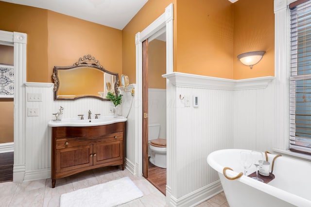 1042 Neil Ave, Columbus, OH 43201 - bathroom with wainscoting, a freestanding tub, toilet, and vanity