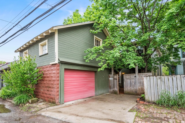 1042 Neil Ave, Columbus, OH 43201 - view of side of home featuring concrete driveway, fence, and an attached garage