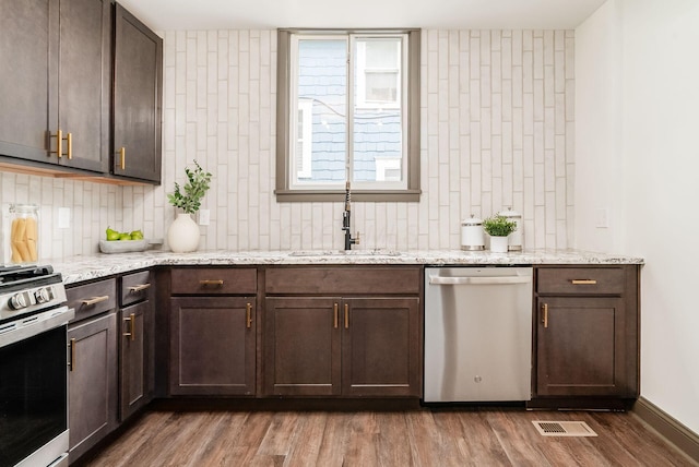 46 E Markison Ave, Columbus, OH 43207 - kitchen with appliances with stainless steel finishes, a sink, decorative backsplash, dark wood-style flooring, and dark brown cabinetry