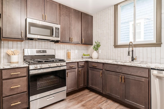 46 E Markison Ave, Columbus, OH 43207 - kitchen featuring appliances with stainless steel finishes, a sink, backsplash, light wood finished floors, and dark brown cabinets