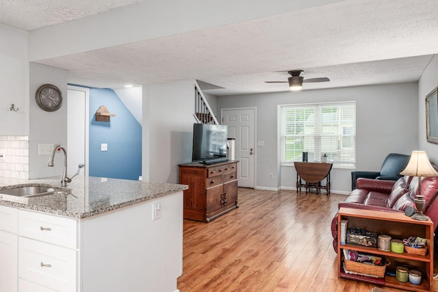 5120 Singleton Dr Unit 36D, Hilliard, OH 43026 - kitchen featuring a sink, light wood-style floors, a textured ceiling, ceiling fan, and light stone countertops