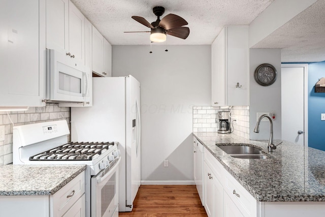 5120 Singleton Dr Unit 36D, Hilliard, OH 43026 - kitchen with white appliances, a sink, a peninsula, white cabinetry, and a textured ceiling