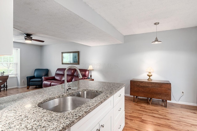 5120 Singleton Dr Unit 36D, Hilliard, OH 43026 - kitchen featuring a sink, a textured ceiling, light wood-style flooring, white cabinetry, and light stone counters