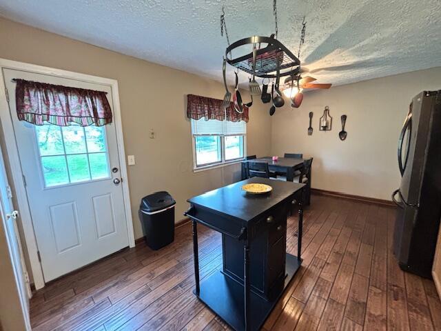 kitchen featuring freestanding refrigerator, hardwood / wood-style floors, a textured ceiling, a ceiling fan, and baseboards
