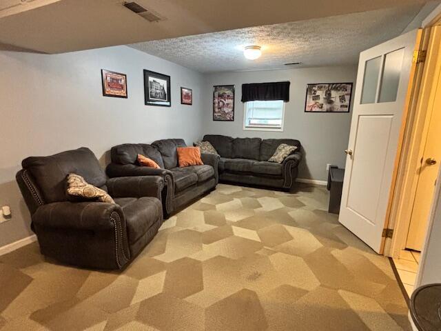living room with light carpet, a textured ceiling, and baseboards