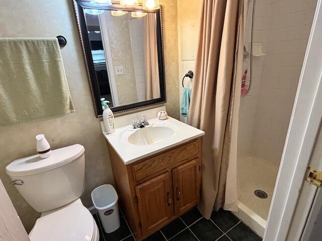 full bathroom featuring toilet, a stall shower, a chandelier, vanity, and tile patterned flooring