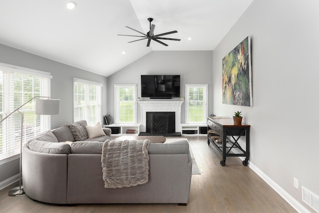living room with a ceiling fan, a fireplace, plenty of natural light, lofted ceiling, and baseboards