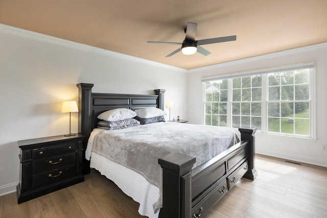 bedroom with crown molding, baseboards, light wood-style flooring, and a ceiling fan