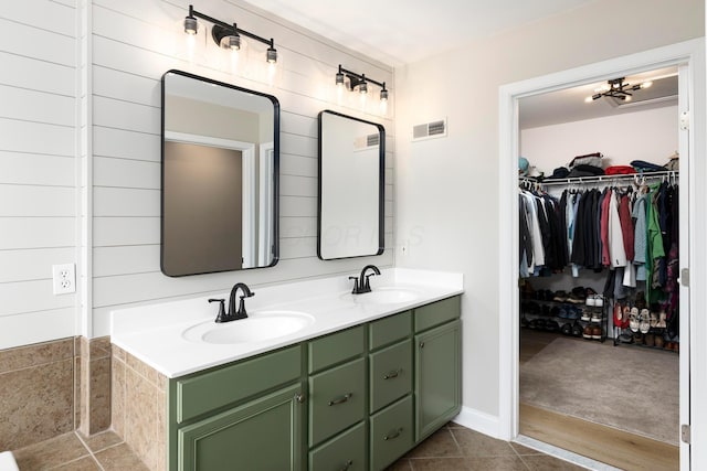bathroom featuring double vanity, a walk in closet, and tile patterned floors