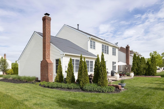 view of home's exterior featuring a chimney, a lawn, and a patio area