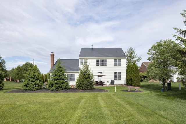 rear view of property featuring a chimney, a yard, and a patio area