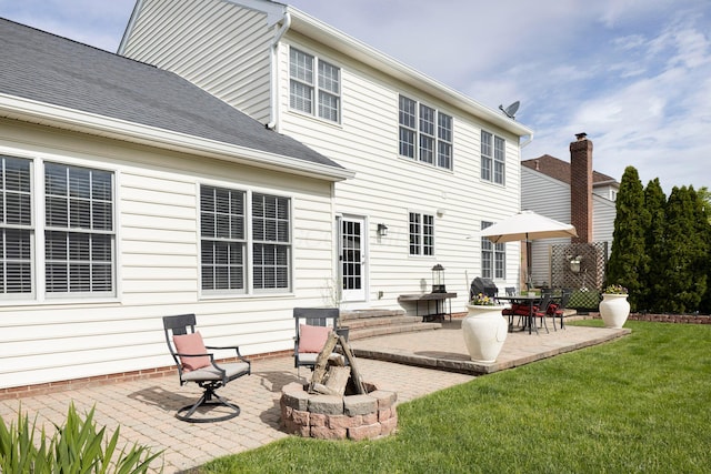 back of house featuring a patio, a lawn, and roof with shingles