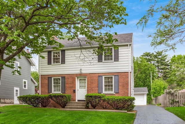colonial home with brick siding, a detached garage, and entry steps