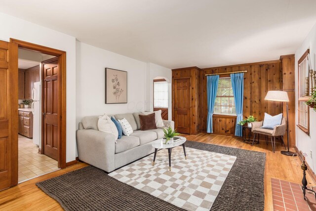 living area featuring light wood finished floors, arched walkways, and wood walls