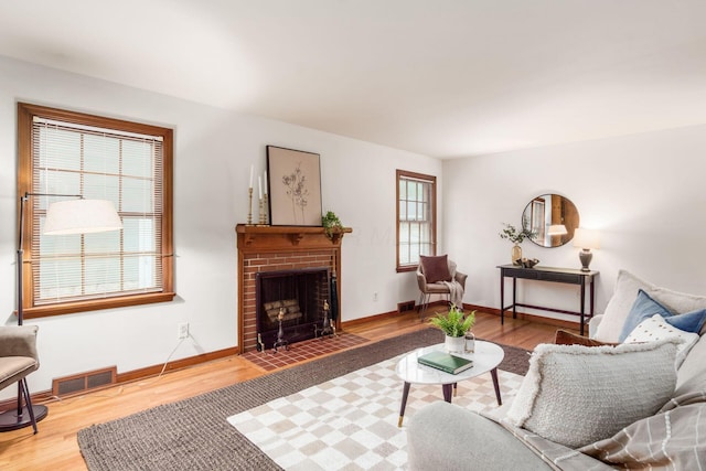 living area with a brick fireplace, wood finished floors, and baseboards